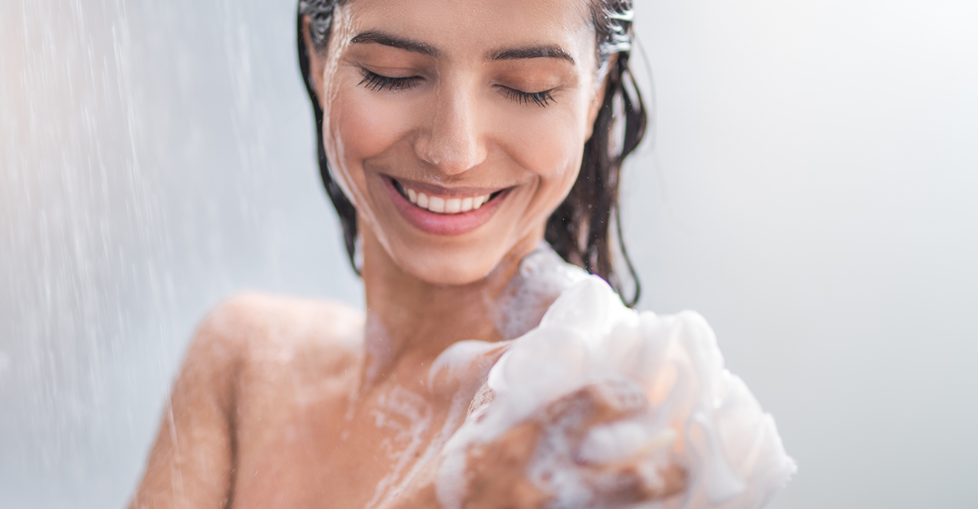 immagine ragazza che sorride, si mette la schiuma per detergere il corpo